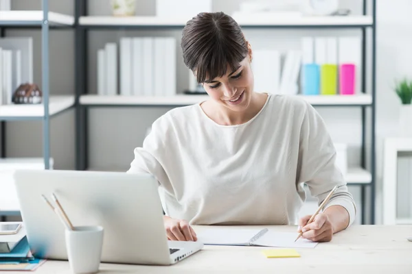 Smiling woman sitting at desk — Stock Photo, Image