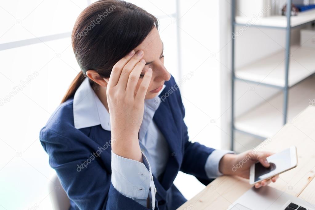 Pensive businesswoman reading sms