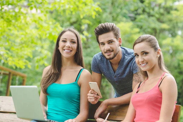 Guy and girls using laptop — Stock Photo, Image