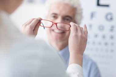 Optician giving new glasses to the patient clipart