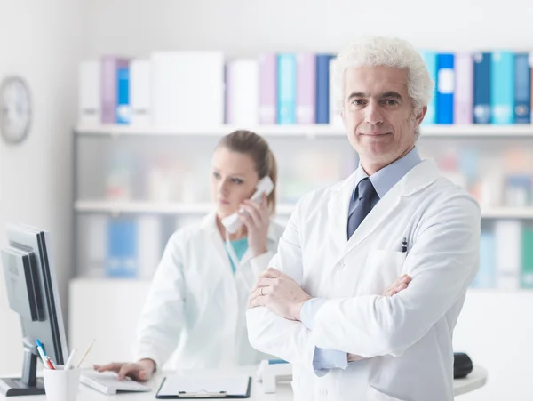 Arzt mit seiner jungen Assistentin im Büro — Stockfoto