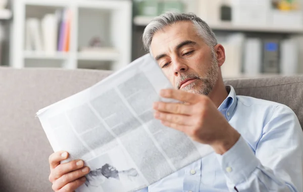 Hombre de negocios leyendo un periódico en casa — Foto de Stock