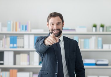 Gülümseyen işadamı kamerayı işaret ediyor