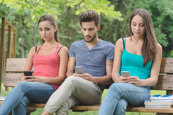 Tieners in het park met behulp van smartphones — Stockfoto