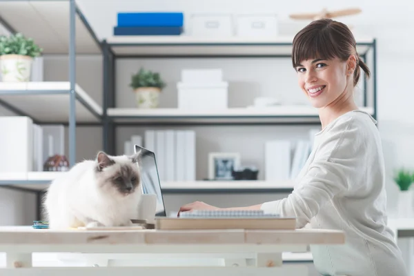 Mulher trabalhando na mesa com seu gato — Fotografia de Stock