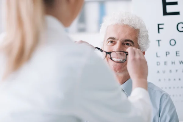 Optician giving new glasses to the patient — Stock Photo, Image