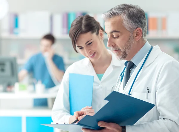 Médico revisando registros médicos con su asistente —  Fotos de Stock