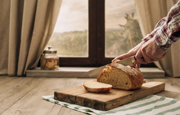 Homem cortando um pão fresco — Fotografia de Stock