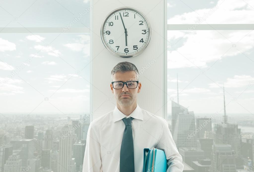 Frustrated businessman standing under a clock