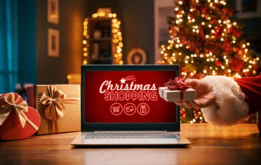 Noel Baba eve bir hediye ve dizüstü bilgisayarla Noel alışveriş reklamı getiriyor.