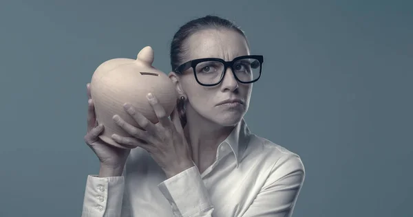 Woman checking her deposit in a money box, savings and investments concept