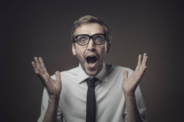 Şok olmuş genç iş adamı ellerini kaldırmış kameraya bakıyor ve nefes nefese, müthiş bir sürpriz aldı.