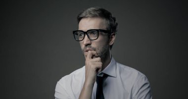 Düşünceli işadamı eli çenesinde, problem çözme ve karar verme konseptiyle düşünüyor