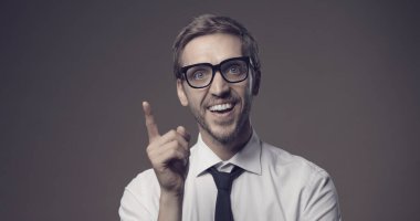 Zeki iş adamının harika bir fikri var ve işi için bir çözüm buluyor, gülümsüyor ve yukarıya doğru işaret ediyor.