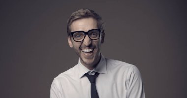 Mutlu iş adamı yüksek sesle gülüyor ve kameraya bakıyor.