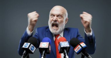 Konuşması sırasında saldırgan bir politikacı, bağırıyor ve yumruklarını gösteriyor.