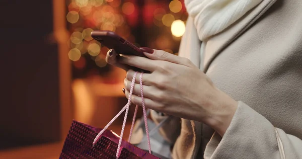 Kobieta Robi Zakupy Świąteczne Nosi Torby Zakupy Używa Aplikacji Mobilnych — Zdjęcie stockowe