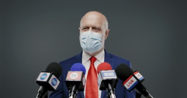Политик снимает маску для лица во время пресс-конференции — стоковое видео