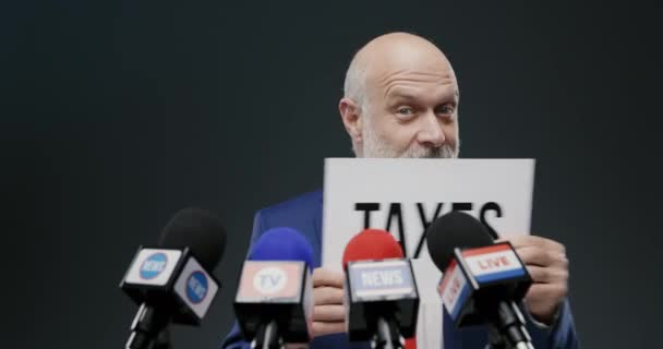 Πολιτικός κρατώντας μια πινακίδα με την έννοια των φόρων — Αρχείο Βίντεο