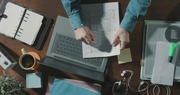 Büroangestellte checkt Papierkram und benutzt einen Laptop — Stockvideo