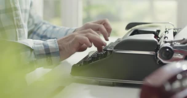 Mannen sitter vid skrivbordet och skriver på en skrivmaskin — Stockvideo
