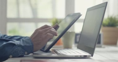 Masada oturup dijital tablet kullanan bir adam.