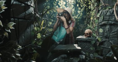 Tropikal bir ormanı keşfeden neşeli turist, antik harabelerin fotoğraflarını çekiyor.