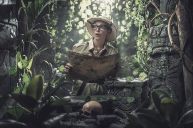 Bir haritayla tropikal bir ormanı keşfeden neşeli bir kadın, bazı antik kalıntılar bulur.