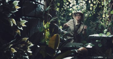 Korkak kâşif ormanda antik kalıntılar buluyor. Elinde bir palayla yürüyor.