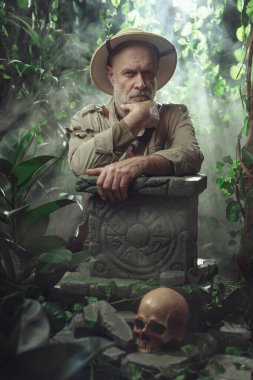 Ormanı ve antik kalıntıları keşfeden cesur bir maceraperest, elleri çenesinde poz veriyor.