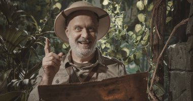 Ormanı keşfeden neşeli bir maceraperest haritaya bakıyor ve harika bir fikri var.