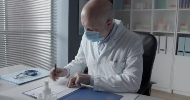 Cerrahi maskeli doktor reçete yazıyor.