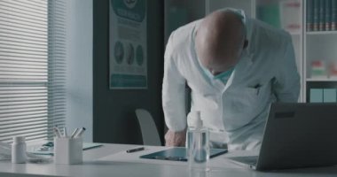 Yorgun doktor maskesini çıkarıyor.