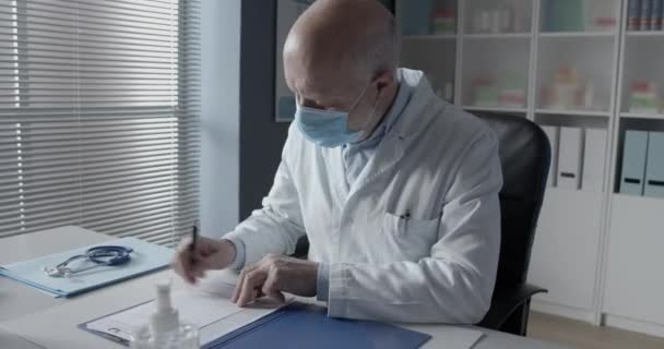 Medico con maschera chirurgica che dà una prescrizione — Video Stock