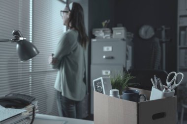 Pensive woman in the office packing her belongings, she has been fired