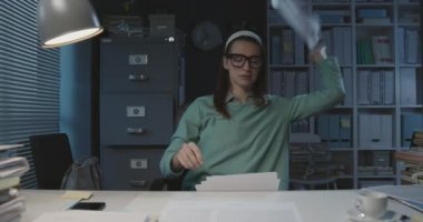 Yorgun bir ofis çalışanı evrakları atıyor.