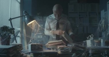 Terk edilmiş ofiste dosya arayan bir işadamı