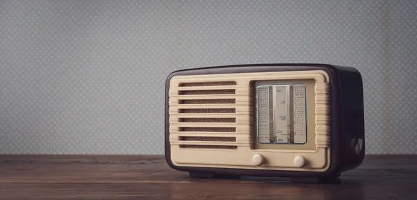 Vintage radio on the table and vintage wallpaper: music and entertainment concept, blank copy space