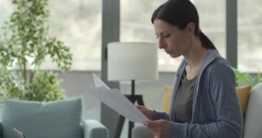 Evde çalışan ve evrakları kontrol eden bir kadın.