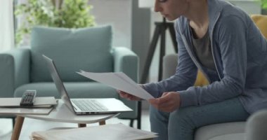 Evde çalışan ve evrakları kontrol eden bir kadın.