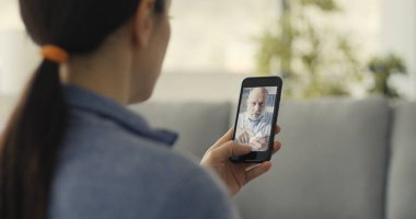 Kadının doktoruyla görüntülü konuşma yapması, teletıp konsepti.