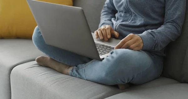 女性は自宅でソファに座って 彼女のラップトップ リモートワークコンセプトとオンラインで接続します — ストック写真