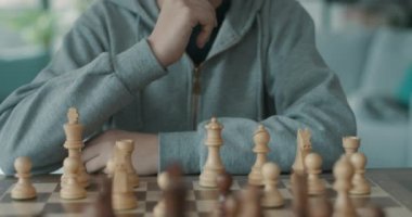 Çocuk satranç oynuyor ve satranç tahtasına bakıyor.