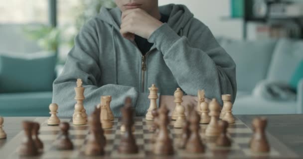 Menino jogando xadrez e olhando para o tabuleiro de xadrez — Vídeo de Stock