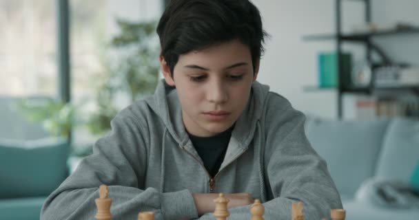 Chico inteligente jugando ajedrez en casa — Vídeo de stock
