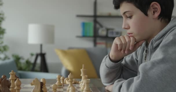 Intelligent boy playing chess at home — Stock Video