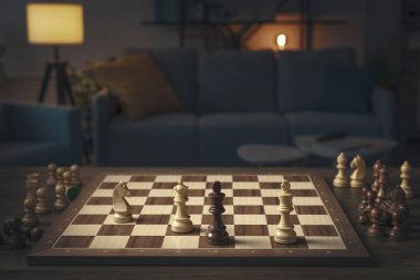 Satranç oyununun parçaları tahtada, iç kısmı da arka planda.
