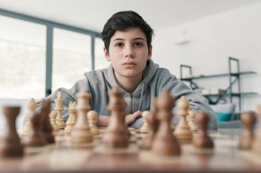 Akıllı çocuk evde satranç öğreniyor, odaklanmış ve düşünüyor.