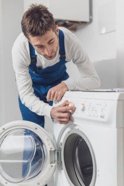 Çamaşır makinesini tamir eden tamirci, profesyonel servis konseptini ayarlıyor.