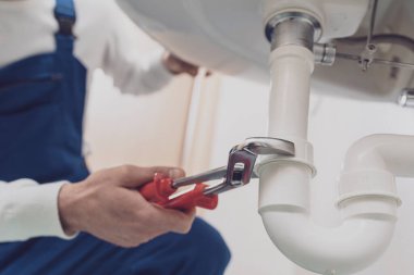 Profesyonel tesisatçı eve lavabo kuruyor ya da tamir ediyor.